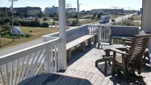 Eine Holzterrasse mit weißer Reling, einer Bank und einem Tisch mit Stühlen.