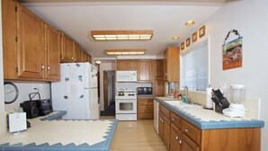 A compact kitchen with wooden cabinets, a refrigerator, a microwave, and a sink. - Spacious 5 bedroom home, 1 block from beach (Avalon)