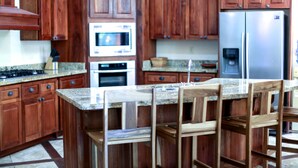 A kitchen with wooden cabinets, a stainless steel refrigerator, a microwave, and a granite countertop.