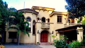A Mediterranean-style building with a central entrance, arched doorways, and a balcony.