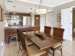 Una cocina moderna con una isla central, electrodomésticos de acero inoxidable y un comedor con una mesa de vidrio y sillas de madera.