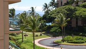 A curved road with palm trees and a building in the background. - ❤️Luxury 2 BD Condo at Honua Kai Resort on the Beach ❤️ (Kaanapali)
