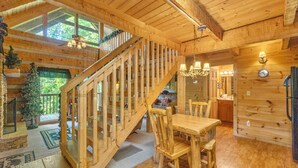 L’intérieur d’un chalet en bois comprend un escalier, un coin repas et une cuisine.