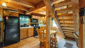 L’intérieur d’une cabane en bois comprend une cuisine, un coin repas et un escalier.