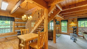 L’intérieur d’un chalet en bois comprend un coin repas, un escalier et de grandes fenêtres.