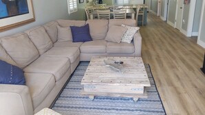 Een woonkamer met een beige modulaire bank, een kamerkleed en een houten salontafel.