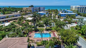 An aerial view of a resort with a swimming pool surrounded by palm trees and a view of the ocean. - Siesta Key private beach access (Sarasota)