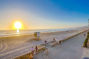 A beach with a lifeguard tower, a bicycle path, and people walking and cycling.