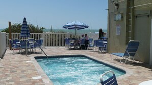 Ein Poolbereich mit blauen Stühlen, einer Whirlwanne und Blick auf das Meer.