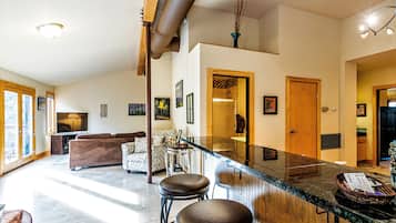 A spacious living area with a large TV, a fireplace, and a dining area with bar stools.