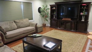 Ein Wohnzimmer mit einer Couch, einem Couchtisch, einem Fernseher und einem Schrank.