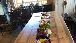 A long wooden table with a variety of cheeses, fruits, and crackers arranged for a buffet. - Exclusive Family Luxury Mountaintop Lodge on 43 acres (Granby)