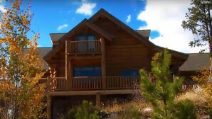 A wooden cabin with a balcony and a second-story window, surrounded by trees and a clear sky. - Exclusive Family Luxury Mountaintop Lodge on 43 acres (Granby)