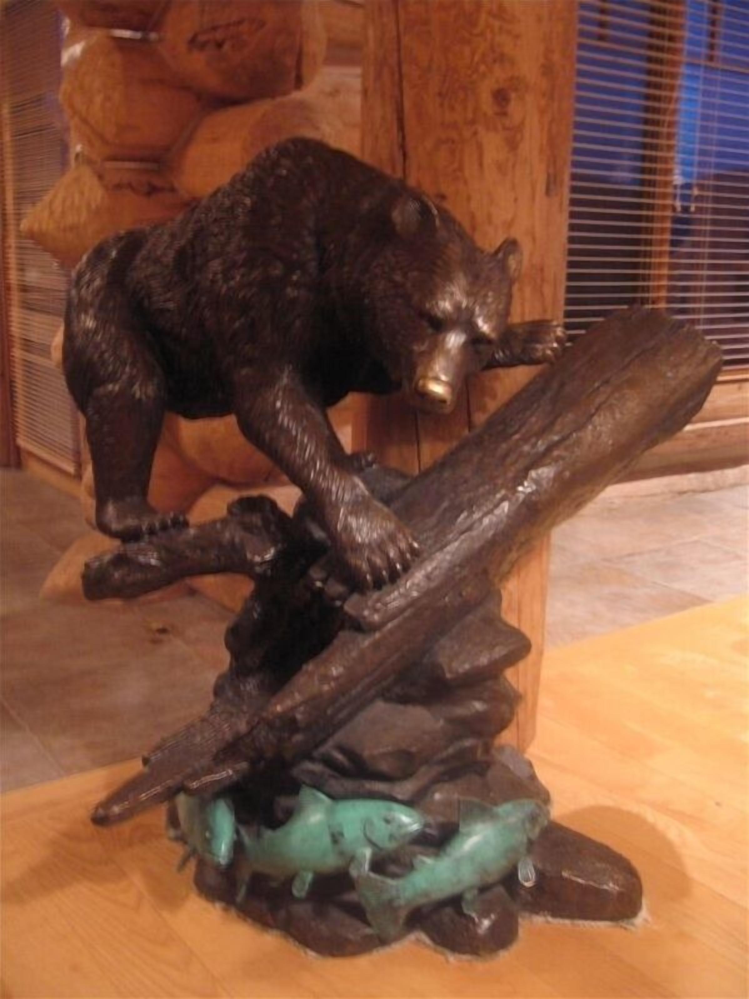 Une sculpture d’ours sur un socle en bois, avec des poissons à la base.