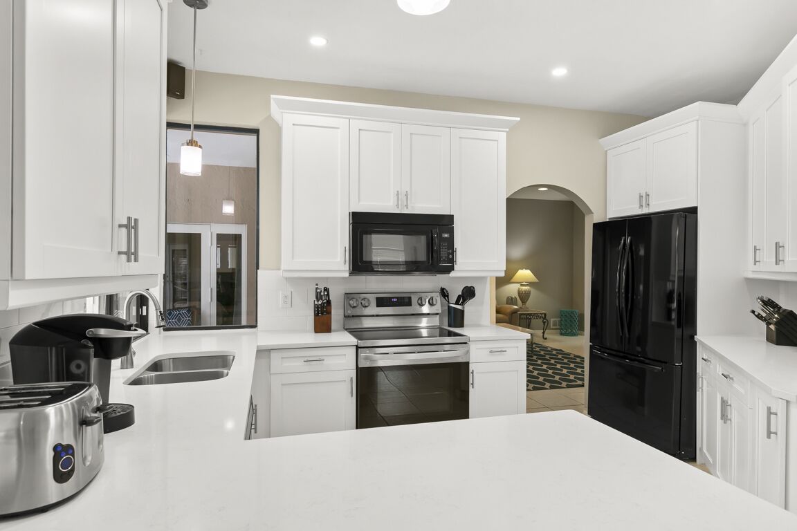 Una cocina moderna con armarios blancos, electrodomésticos de acero inoxidable y una isla central.