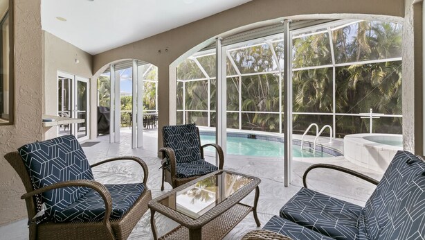 Un espace piscine intérieur aménagé avec des meubles en osier et de grandes fenêtres.