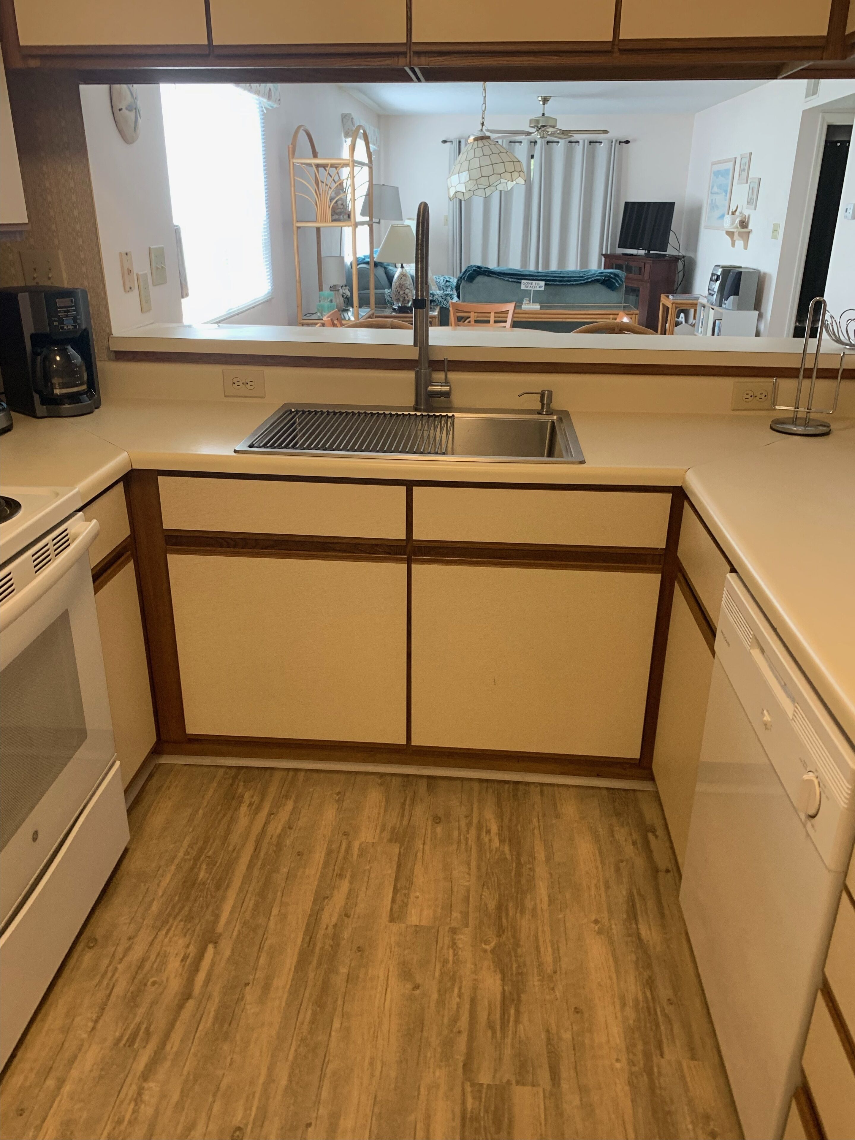 A compact kitchen with a built-in sink, a stove, and a dishwasher.