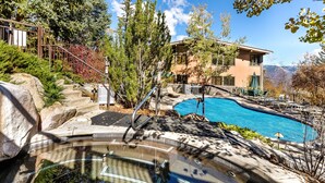 Un espace piscine avec un jacuzzi, des escaliers et un bâtiment offrant une vue sur les montagnes.