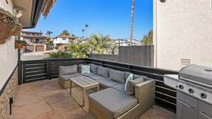 Eine Terrasse mit Sofa, Tisch und Grill.