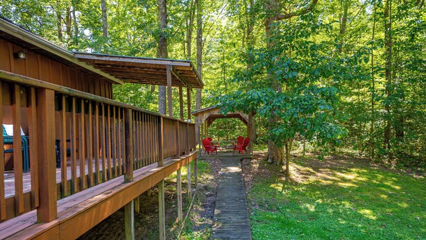 Une terrasse en bois dotée d’un espace salon abrité et d’un chemin menant à un belvédère.