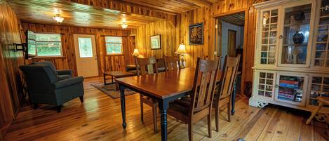 Un interior de madera con una mesa de comedor, sillas y un aparador con puertas de cristal.