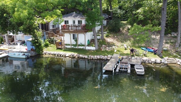 Une propriété au bord du lac, dotée d’un quai, de bateaux et d’une maison avec une terrasse.