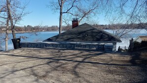 Une maison avec un toit en pente, une cheminée en briques et des fondations en pierre.