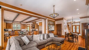 A spacious living room with a large sectional sofa, wooden flooring, and a dining area with a wooden table and chairs. - Villa Del Mare PRIVATE POOL/HOT TUB, OCEAN VIEWS, ELEV! (Isle Of Palms)