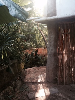 A garden pathway leading to a rustic building with a wooden fence. - Casita Milagros - A Jungle Tree House (Tulum)