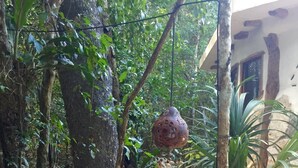 Un jardín tranquilo con una estatua de Buda, abundante vegetación y una maceta colgante decorativa.