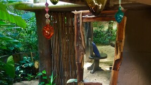 Un espacio al aire libre rústico con una estructura de madera, una mesita y una planta en maceta.