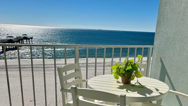 A balcony with a table and chairs, overlooking a beach and the sea. - Save 10% Last min & Week! Gulf Front, Panoramic Views, Beach Supplies, Pool! (Orange Beach)