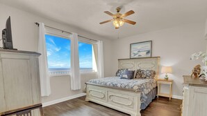A bedroom with a bed, a ceiling fan, a window with curtains, a bedside table, and a dresser. - Less Crowds More Paradise! Enjoy Sea View at the Shores of Panama  2 br, 2 bath (Panama City Beach)