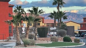 A residential area with palm trees, a fenced parking area, and a mountain range in the background. - Clean & Cozy Condo with pool and trailer parking! (Mesquite)