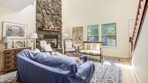 A living room with a stone fireplace, a sofa, a chair, and a coffee table. - Walk to Downtown from this Spacious Home (Napa)