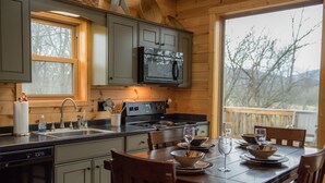 Cocina de cabaña de madera con estufa, lavamanos y comedor.