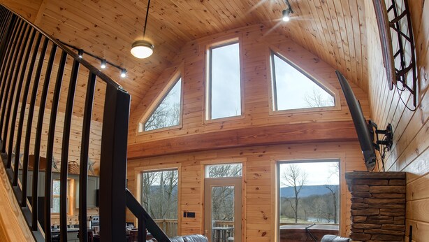 Un interior de madera con una escalera, una chimenea de piedra y vistas al exterior.