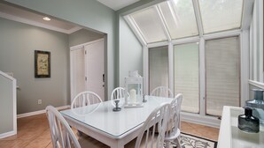 A dining area with a glass table, white chairs, and a candle centerpiece. - Golf cart, newly renovated villa, pet friendly! (Destin)
