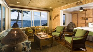 Una habitación con vistas al océano, muebles de mimbre y una cama con almohada verde.