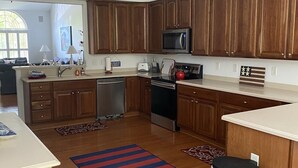 A modern kitchen with wooden cabinets, stainless steel appliances, and a central island. - Updated with everything you need for family fun time, just minutes to beach! (Ocean View)