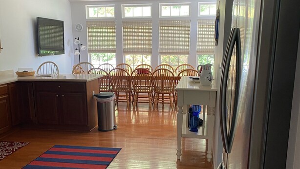 A spacious kitchen with a refrigerator, wooden dining table, chairs, and a large window with blinds. - Updated with everything you need for family fun time, just minutes to beach! (Ocean View)