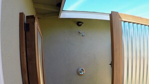 Eine Holzterrasse mit Metallgeländer, einer Tür und einem kleinen Fenster.