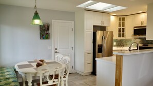 Eine moderne Küche mit weißen Schränken, einem Edelstahlkühlschrank und einer eingebauten Kochinsel mit Spüle.