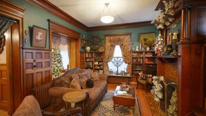 A cozy living room with a fireplace, a Christmas tree, and a bookshelf filled with books.