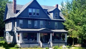 A large, two-story house with a porch, a chimney, and a sign that reads "A Gracious Inn."