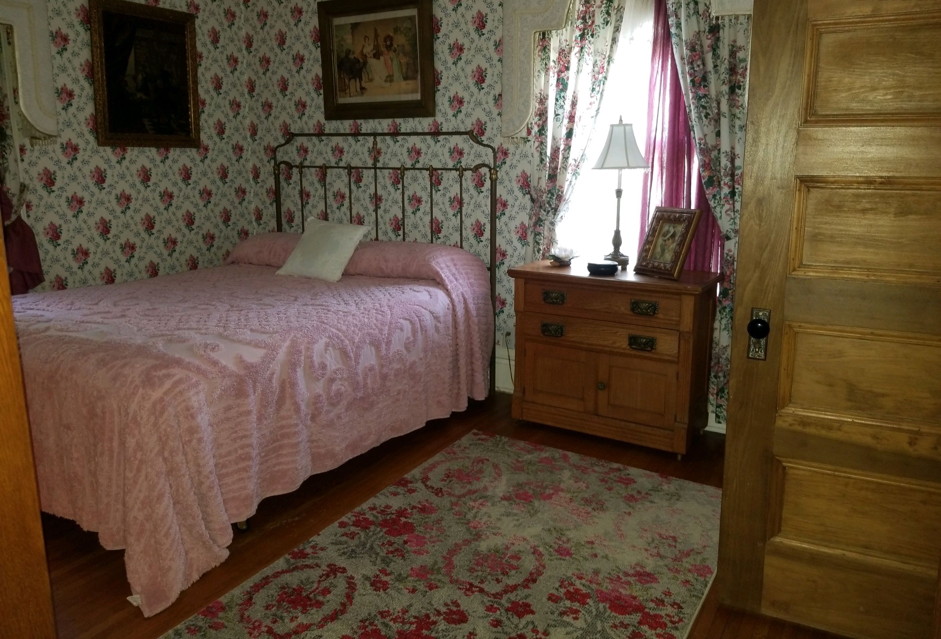 Ein Schlafzimmer mit Bett, Kommode und einer Tür.