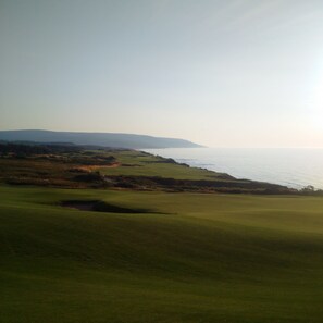 A golf course with a view of the ocean and distant hills. - MacEachern 19th Hole Celtic House (Creignish)