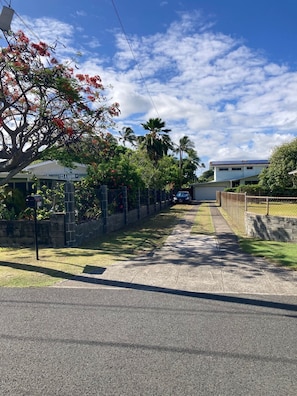 A street view with a sidewalk, a street sign for 123 A Kaimi St, and a building with a blue roof in the background. - NUC 90/BB-0069, GE-014-134-8864-01, TA-014-134-8864-01 (Kailua)