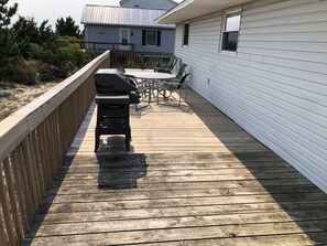 A wooden deck with a grill, outdoor furniture, and a house in the background. - Summer getaway.  Right on the water.  3 bedrooms pets permitted. (Milton)