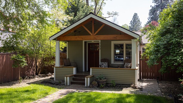 A small, single-story house with a front porch, a door, and a window.
